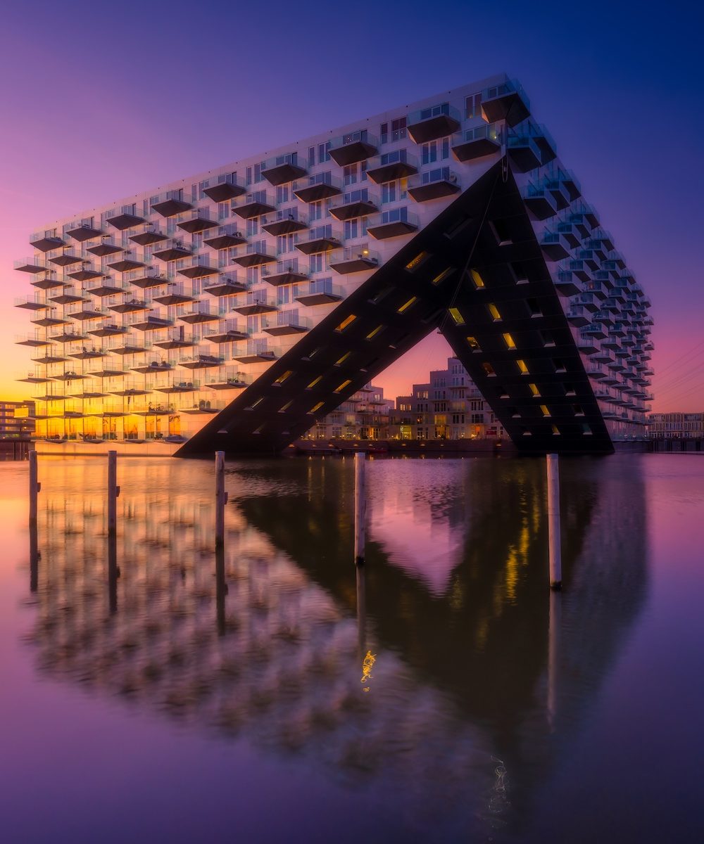 Amsterdam, Netherlands. Cityscape during sunset. Reflection on the water surface. Apartment building near the water in the bay. Architecture of the Netherlands.