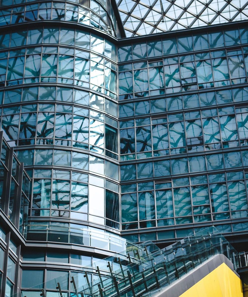 Modern architectural glass facade with geometric patterns and reflections in an urban setting.