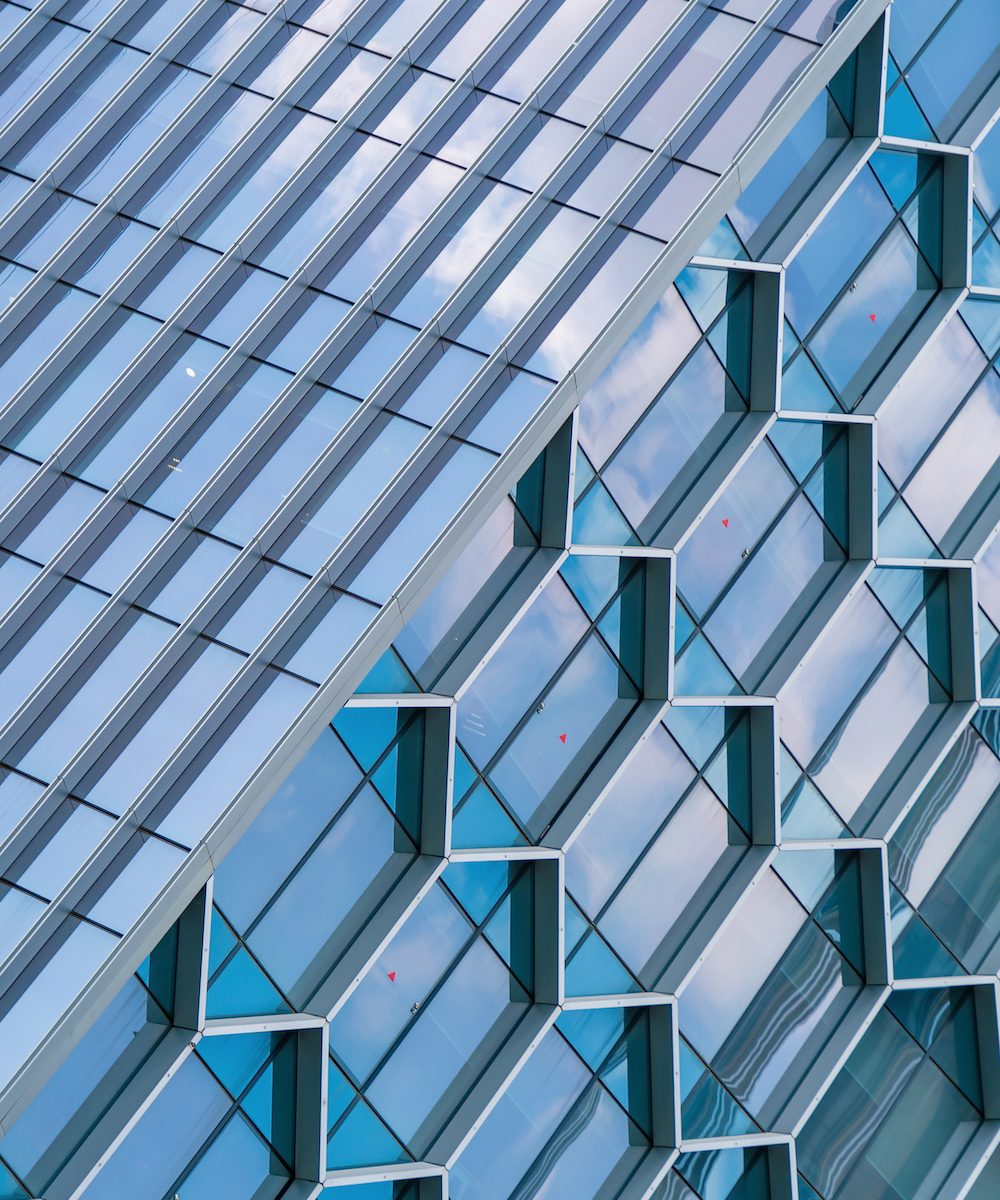 Office buildings. Structure of hexagon windows in futuristic technology network connection concept. Blue glass modern architecture facade design with reflection of sky in urban city, Downtown.
