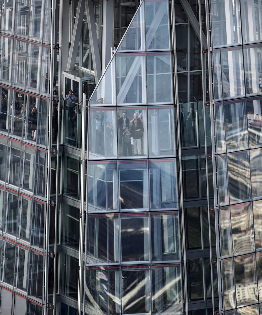 Tourists enjoying a view from a glass elevator in a modern skyscraper.